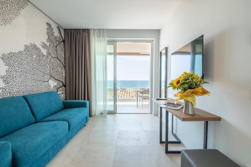 un salon avec un canapé bleu et une table dans l'établissement Residence Panorama Apart Hotel, à Bibione