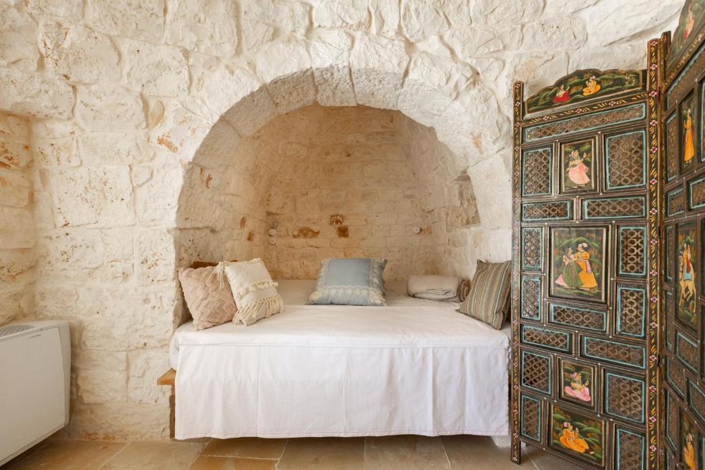 une chambre avec un lit dans un mur de pierre dans l'établissement Trullo Parthenope by Perle di Puglia, à Ostuni 36 autres photos