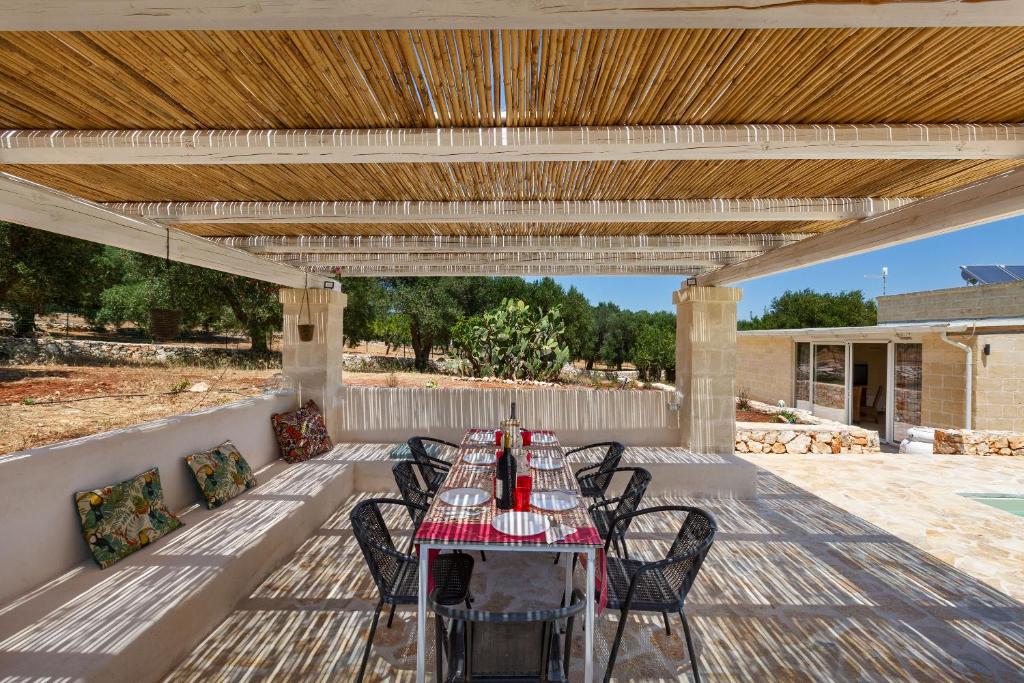 un patio avec une table et des chaises sous une pergola en bois dans l'établissement Trullo Parthenope by Perle di Puglia, à Ostuni