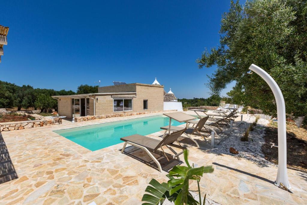 une piscine avec des chaises longues à côté d'une maison dans l'établissement Trullo Parthenope by Perle di Puglia, à Ostuni