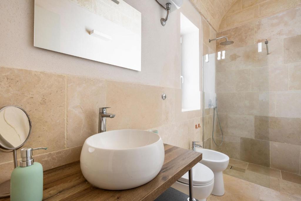 une salle de bain avec un lavabo et des toilettes dans l'établissement Trullo Parthenope by Perle di Puglia, à Ostuni