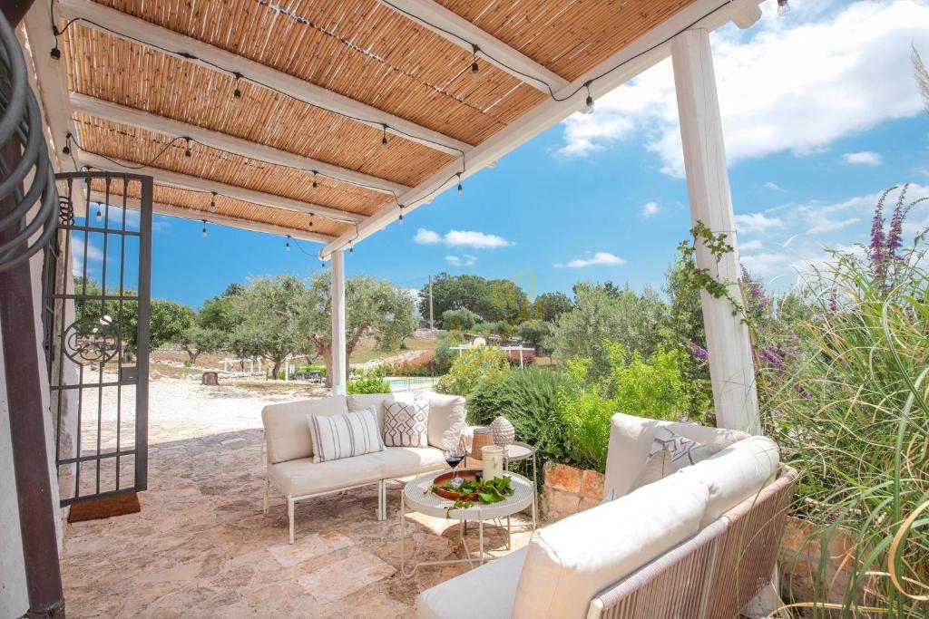 Elle comprend une terrasse dotée d'un mobilier blanc et d'une pergola en bois. dans l'établissement TD Trulli Altura with Pool & Stunning Sunsets, à Martina Franca