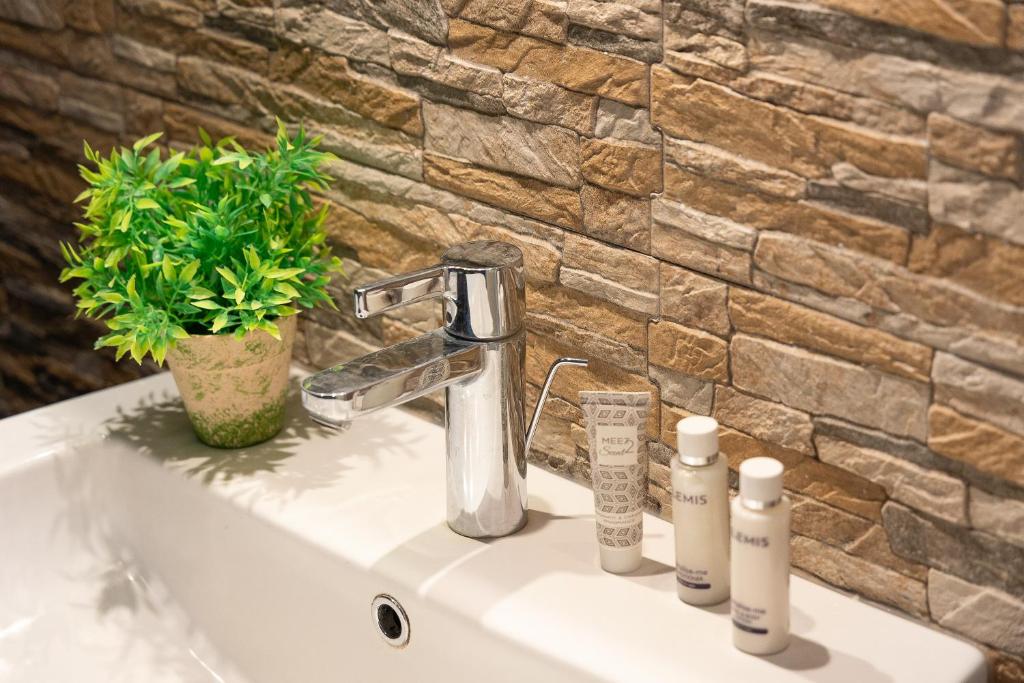 La salle de bains est pourvue d'un lavabo, d'un robinet et d'un mur en pierre. dans l'établissement Villa Saturnia - Piscina Privata - 9' dalle Terme, à Capanne