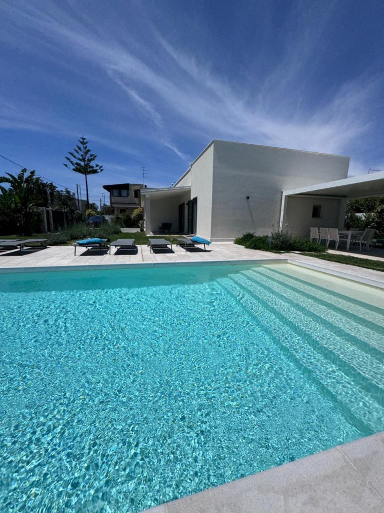 une grande piscine devant une maison dans l'établissement Casa del Sol Luxury Estate Puglia, à Leporano Marina