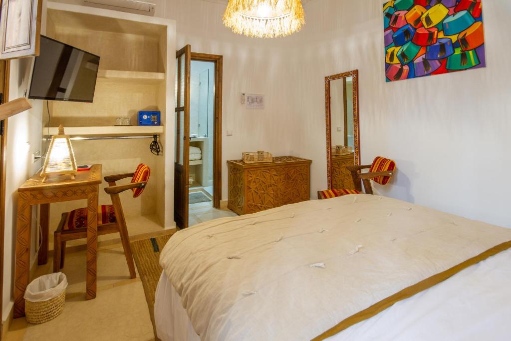une chambre avec un lit, un bureau et une télévision dans l'établissement Riad Bab Aljana, à Marrakech