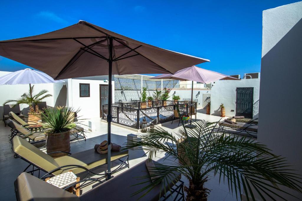 une terrasse avec des chaises, un parasol et des plantes dans l'établissement Riad Bab Aljana, à Marrakech