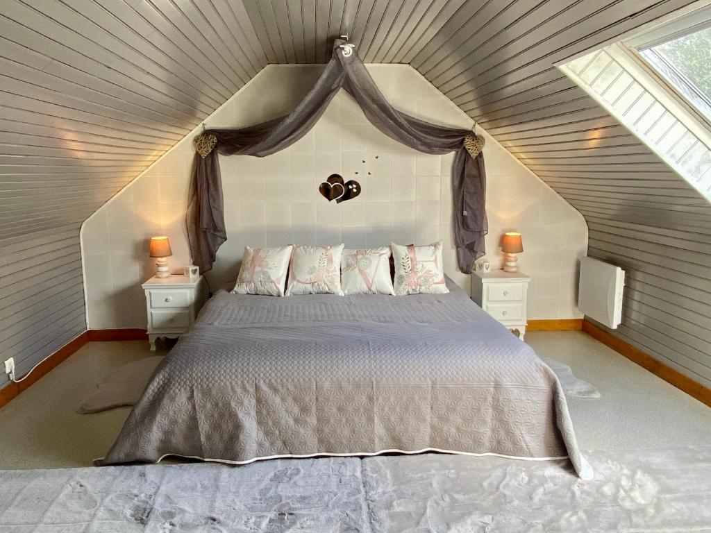 une chambre avec un grand lit dans un grenier dans l'établissement Gîte Breizh piscine ou jacuzzi, à Saint-Évarzec