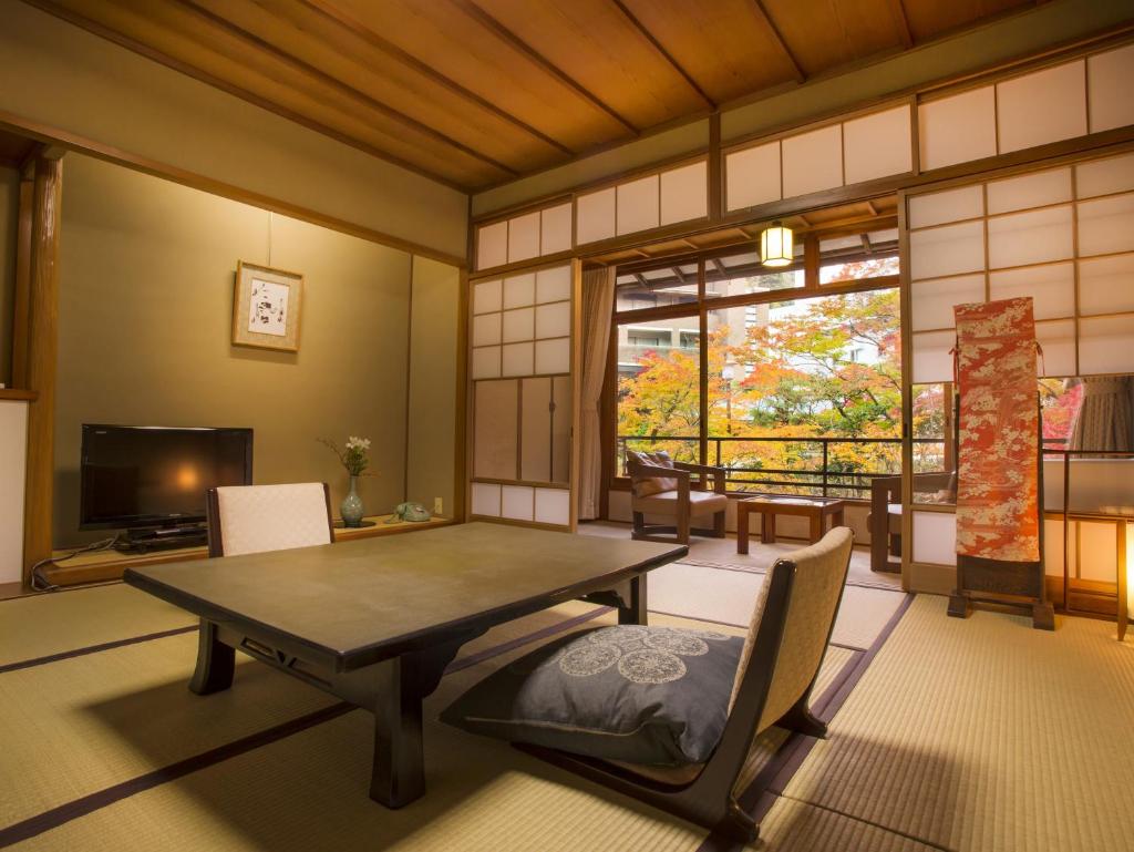 une pièce avec une table, des chaises et une télévision dans l'établissement Hashinoya Bekkan Ransui, à Kobe