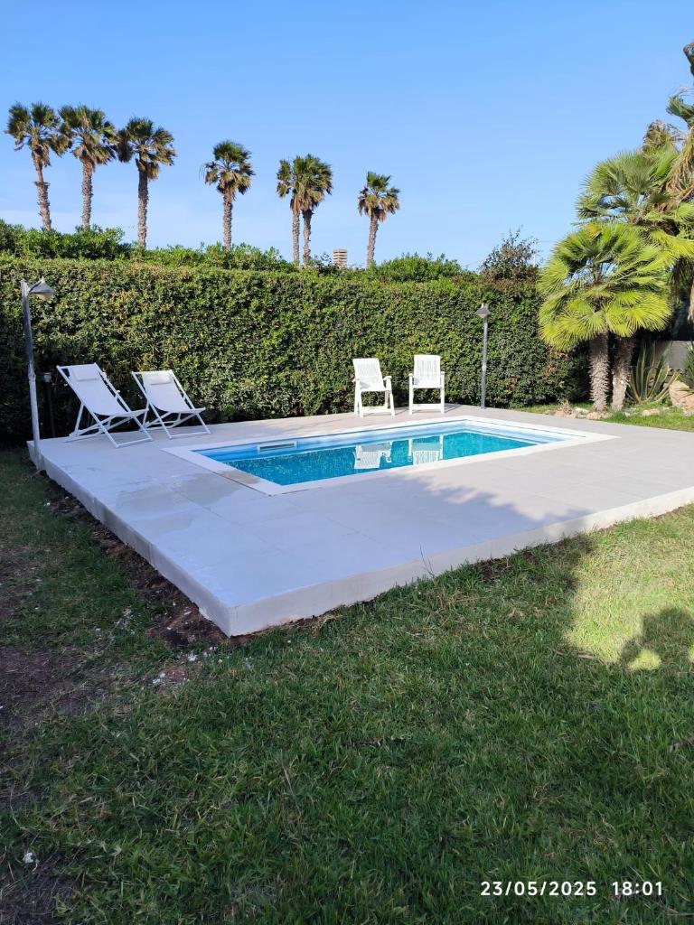 - une piscine avec 2 chaises longues et une piscine dans l'établissement Villa Amos Marzamemi San Lorenzo, à Reitani