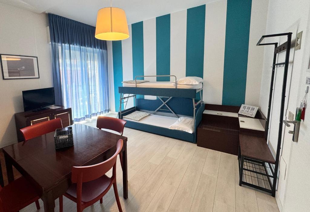 Cette chambre dispose d'une table à manger et de lits superposés. dans l'établissement Regina Urban Beach Hotel, à Lido di Jesolo
