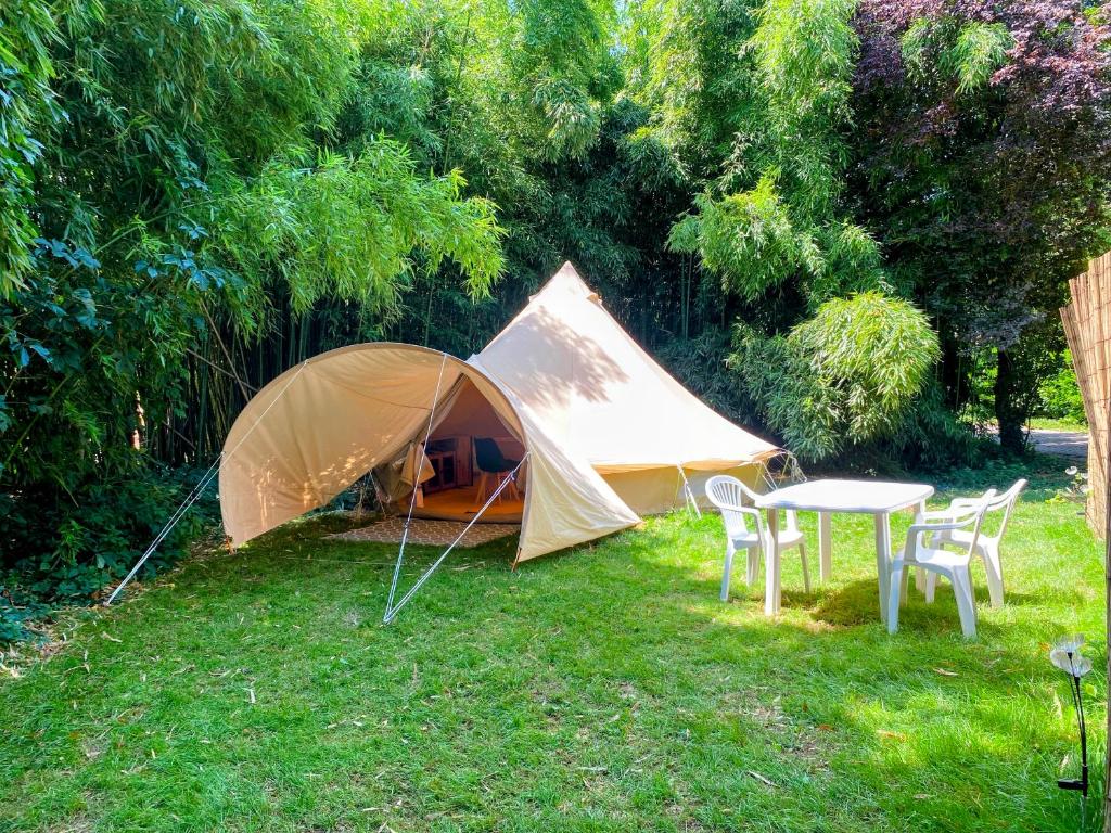 une tente avec des chaises et une table dans l'herbe dans l'établissement Camping les Avenières, à Manthes