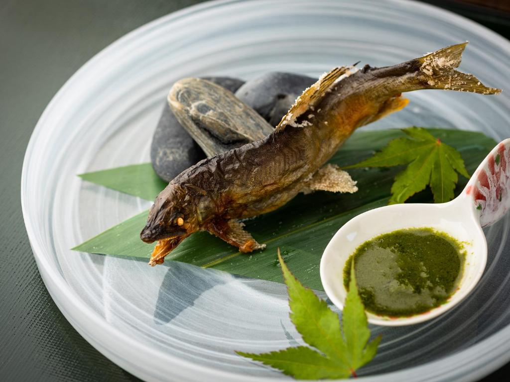 une assiette de nourriture avec deux poissons et quelques pierres dans l'établissement TSUCHIYA Kinosaki onsen, à Toyooka