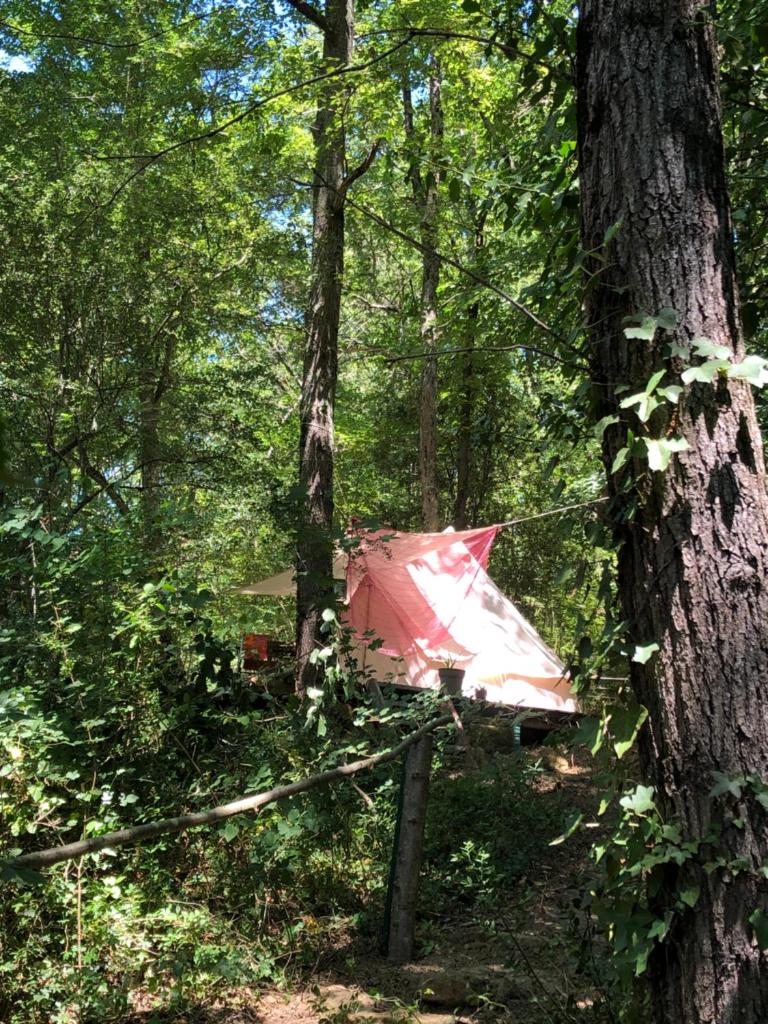 une tente rouge au milieu d'une forêt dans l'établissement Tente aménagée pour 1 ou 2 personnes, à Rennes-les-Bains