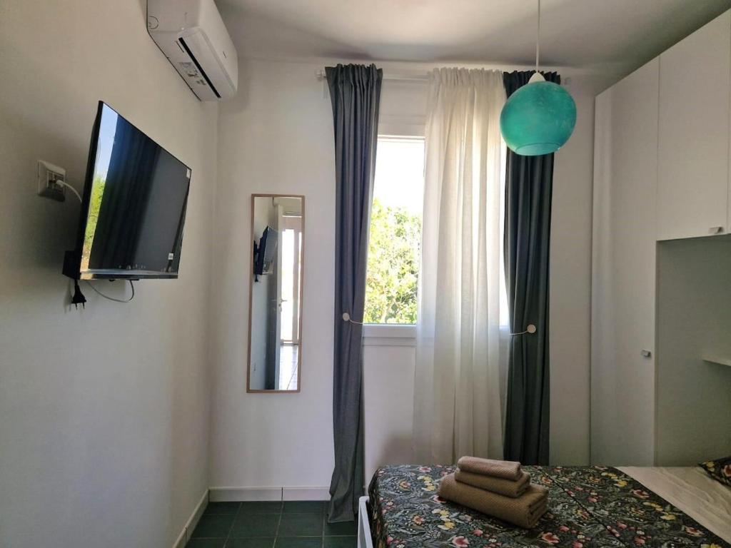 - une chambre avec un lit, une télévision et une fenêtre dans l'établissement Villa Livio, à San Pietro in Bevagna