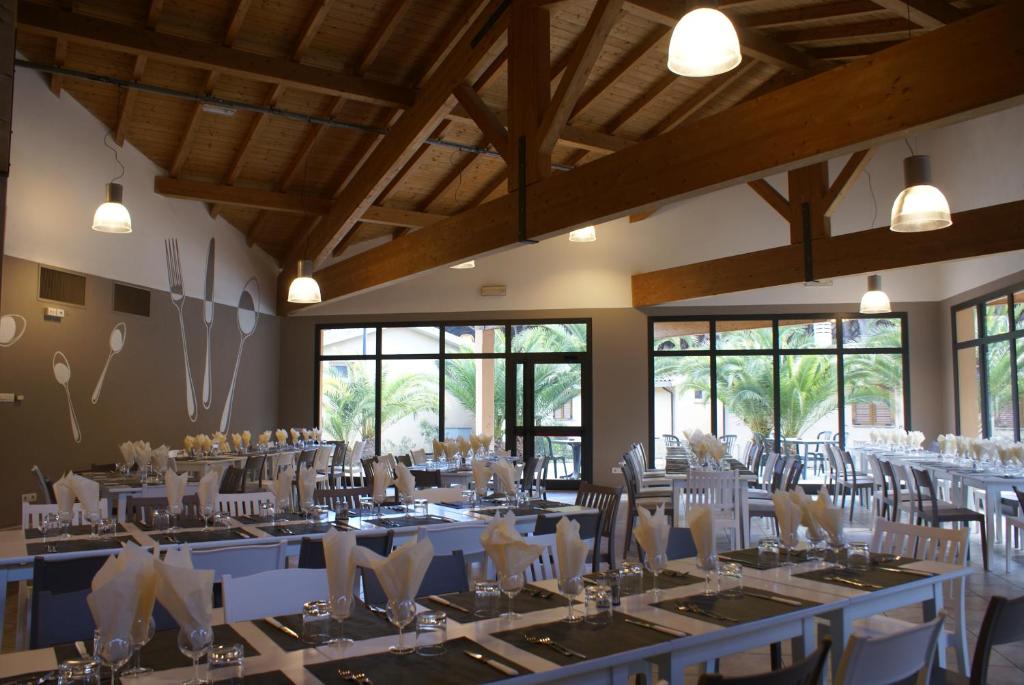 une salle de banquet avec des tables et des chaises blanches dans l'établissement Golfo di Maremma Village, à Albinia