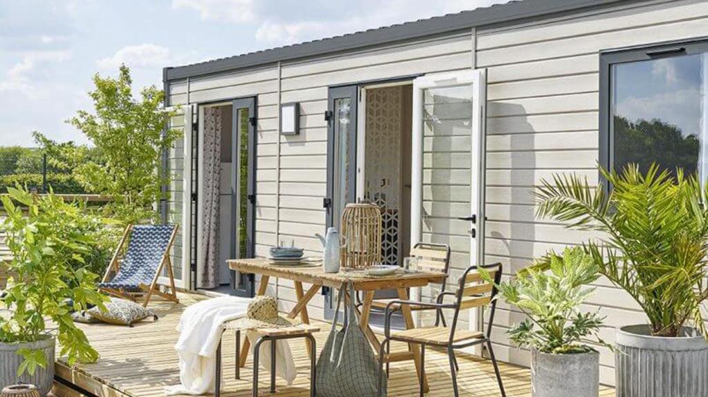 une terrasse avec une table et des chaises ainsi qu'une maison dans l'établissement Camping Les Palmiers, à Hyères