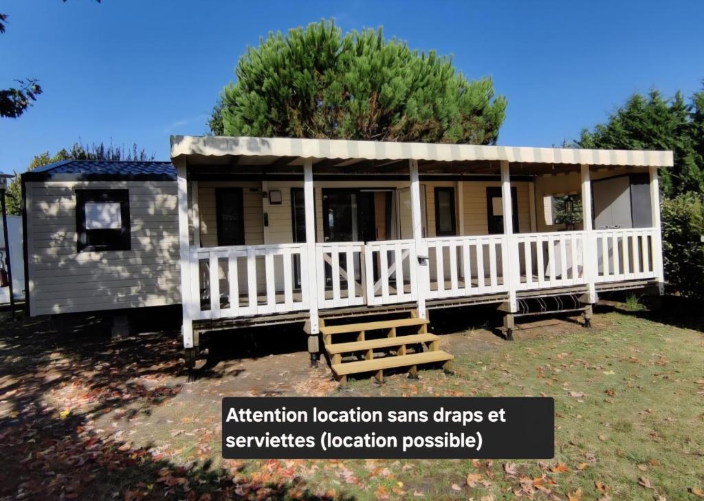 une petite maison avec une clôture blanche et une terrasse couverte dans l'établissement Bungalows soit en 3 ou 4ch - 2 à 10 places - mh732 3ch ou mh828 4ch océan proche Biscarrosse, à Gastes