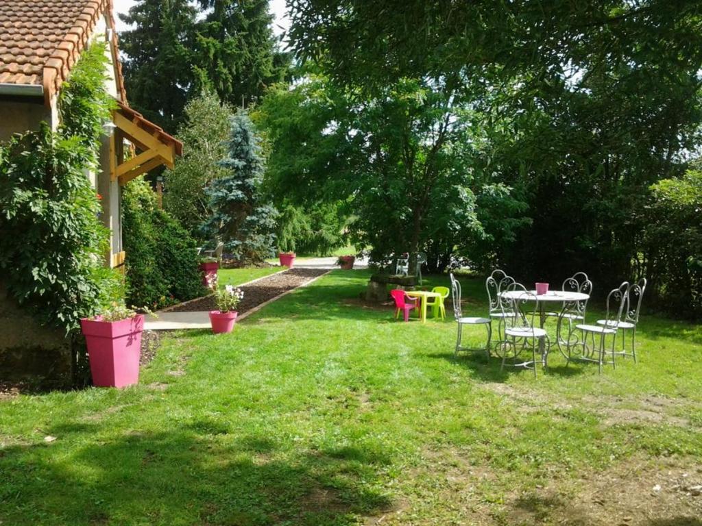 une cour avec une table et des chaises dans l'herbe dans l'établissement Maison rénovée avec parc, piscine partagée et activités pour enfants - Draps et linge offerts - FR-1-489-324, à Moulins