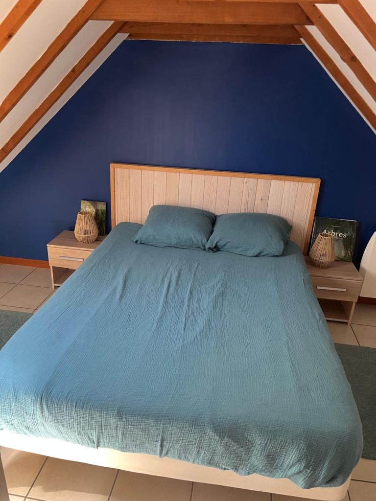 une chambre bleue avec un lit avec un mur bleu dans l'établissement Le Gîte de Kergavan - Une pause entre ciel et mer, à Poullan-sur-Mer