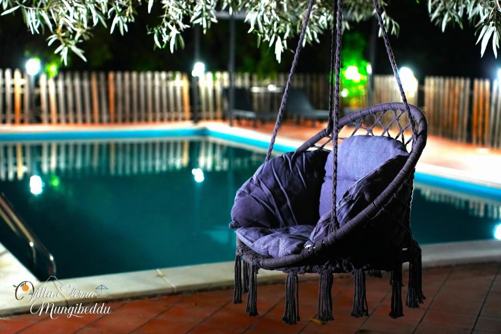 une chaise pivotante au bord d'une piscine la nuit dans l'établissement Villa Eterna Mungibeddu, à Paterno 36 autres photos
