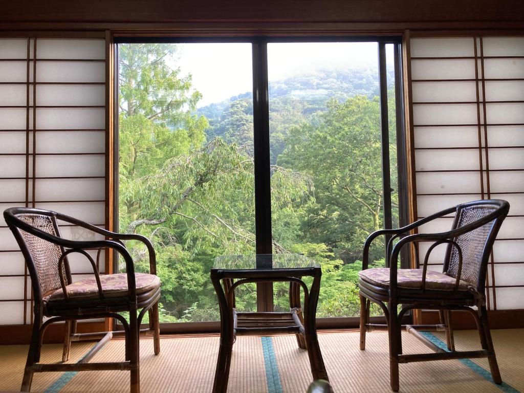 deux chaises et une table devant une fenêtre dans l'établissement HOTEL LT Kitchen Yugawara, à Yugawara