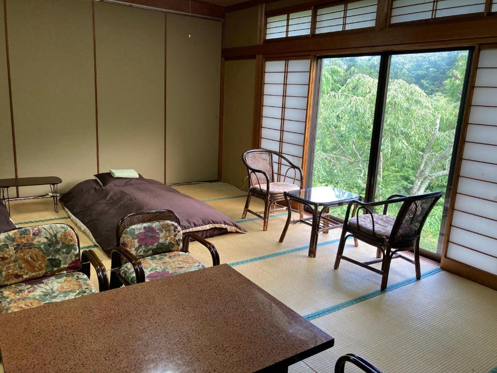 une chambre avec des chaises, des tables et une grande fenêtre dans l'établissement HOTEL LT Kitchen Yugawara, à Yugawara