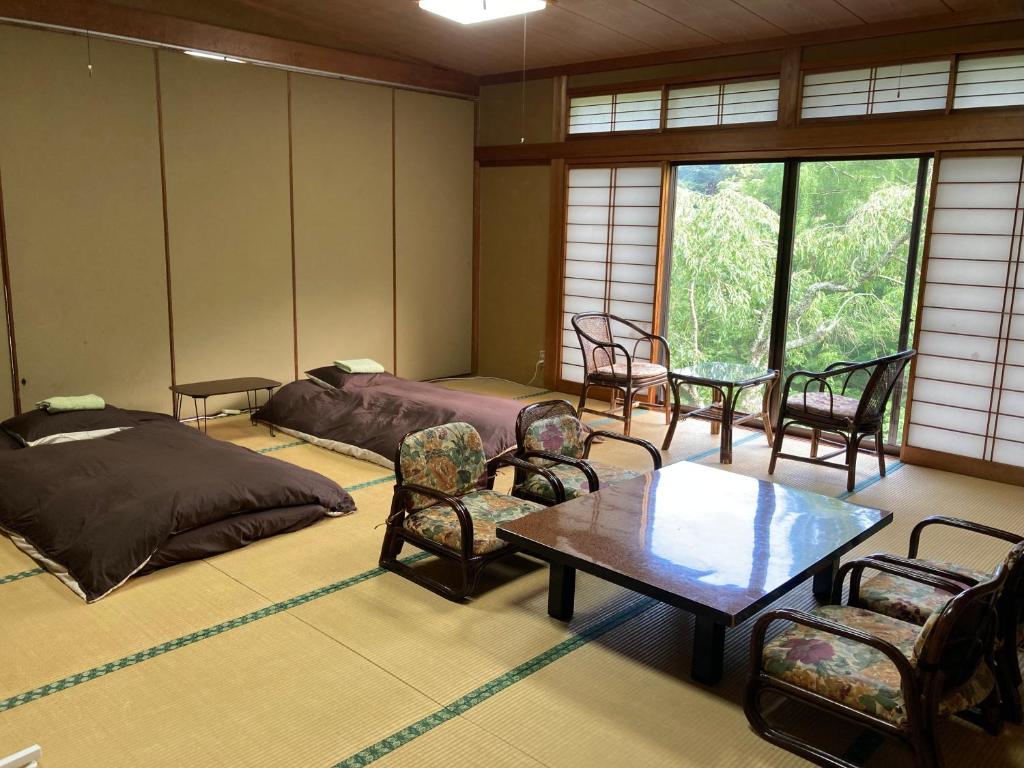 une chambre avec un lit, une table et des chaises dans l'établissement HOTEL LT Kitchen Yugawara, à Yugawara