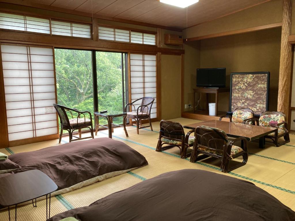 une chambre avec deux lits, une table et des chaises dans l'établissement HOTEL LT Kitchen Yugawara, à Yugawara