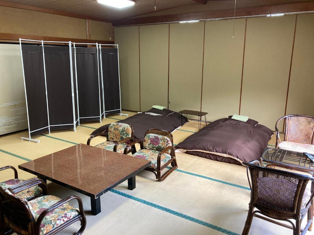 Cette chambre comprend 2 lits, des chaises et des tables. dans l'établissement HOTEL LT Kitchen Yugawara, à Yugawara