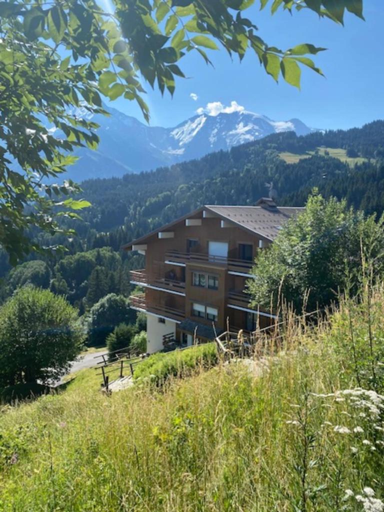un bâtiment sur une colline avec des montagnes en arrière-plan dans l'établissement T2 with pool in Saint-Gervais-les-Bains, à Saint-Gervais-les-Bains