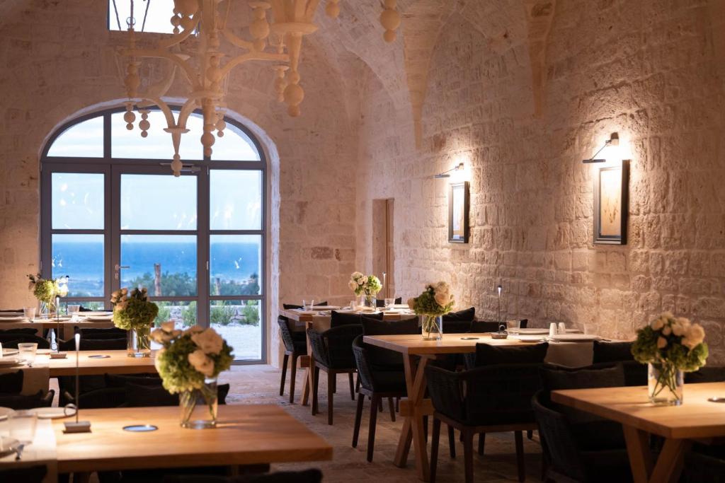 un restaurant avec des tables et des chaises et une grande fenêtre dans l'établissement Masseria Auraterrae, à Polignano a Mare
