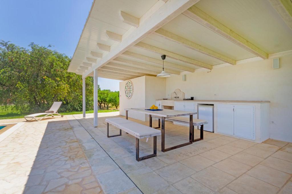 un patio avec une table et des bancs et une cuisine dans l'établissement Country House La Rossi with pool Gallipoli 7, à Gallipoli