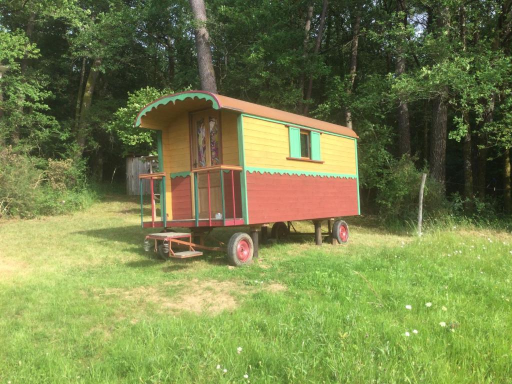 Une petite voiture de train assise dans l'herbe dans l'établissement La roulotte du bonheur, à Saint-Pardoux-la-Rivière