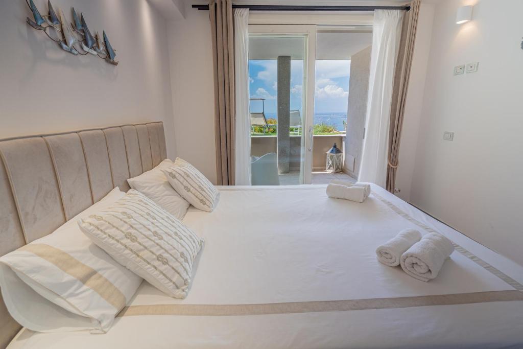 Elle comprend un grand lit blanc avec deux oreillers et une fenêtre. dans l'établissement Villa La Gioia, à Terra Mala 60 autres photos