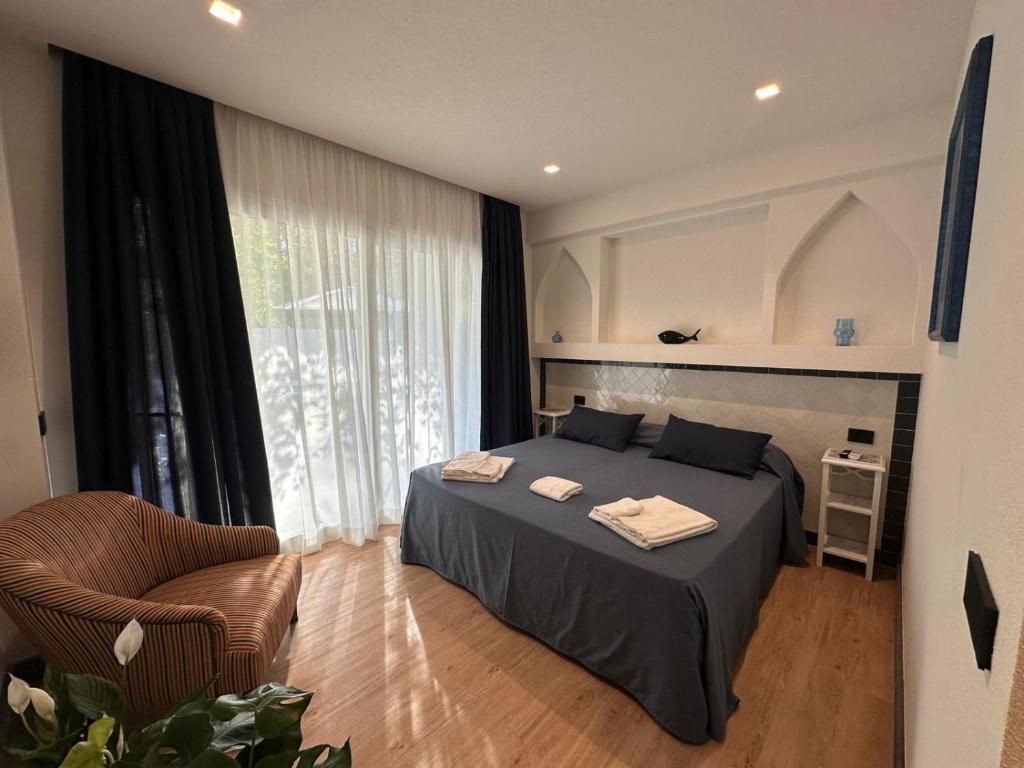 une chambre avec un lit, une chaise et une fenêtre dans l'établissement Le Dune Sicily Hotel, à Catane