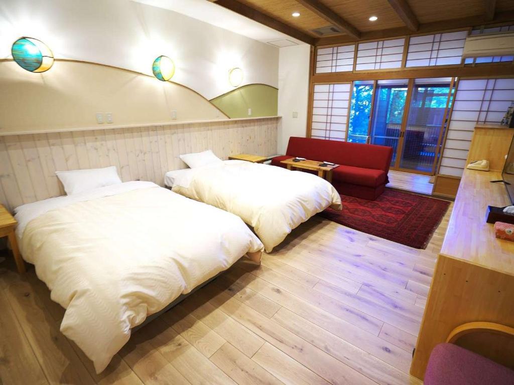 - une chambre avec deux lits et un canapé rouge dans l'établissement Kamiyamada Hotel, à Chikuma 77 autres photos