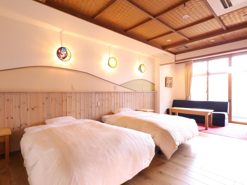 une chambre avec deux lits et un canapé dans l'établissement Kamiyamada Hotel, à Chikuma