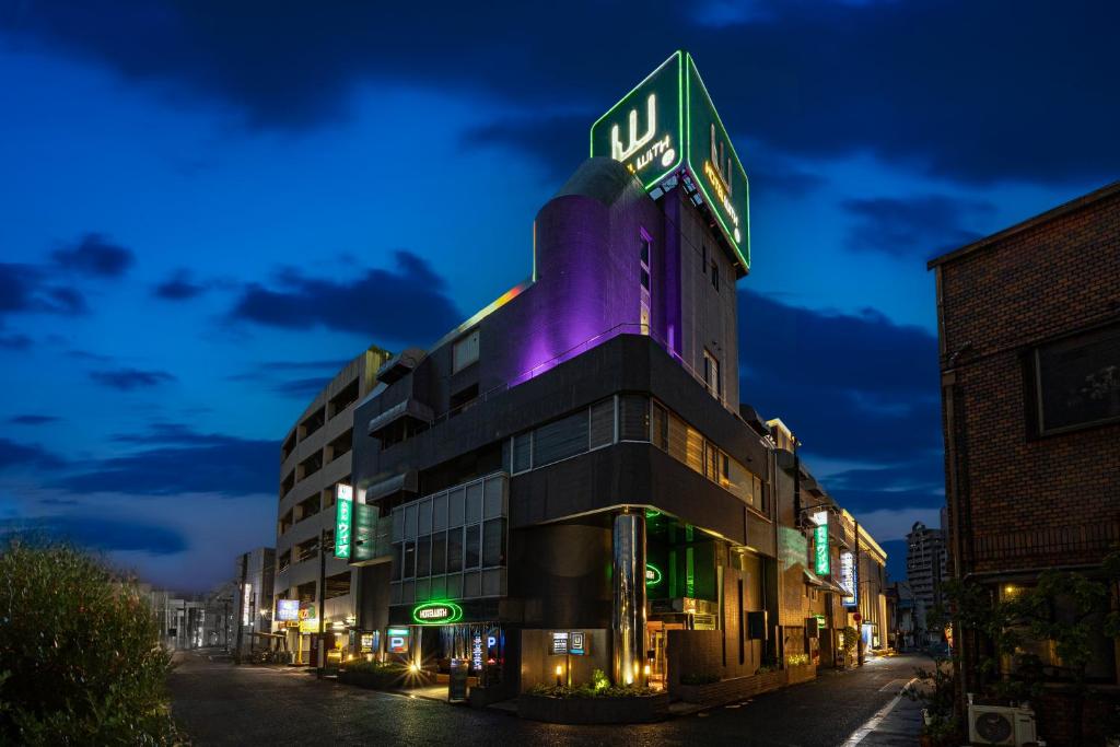 Un bâtiment avec un panneau de néon en haut. dans l'établissement ホテル ウィズ男塾ホテルグループAdult Only, à Fukuyama