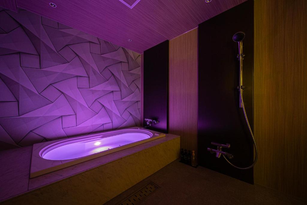 une salle de bain violette avec une baignoire avec un mur géométrique dans l'établissement ホテル ウィズ男塾ホテルグループAdult Only, à Fukuyama 14 autres photos
