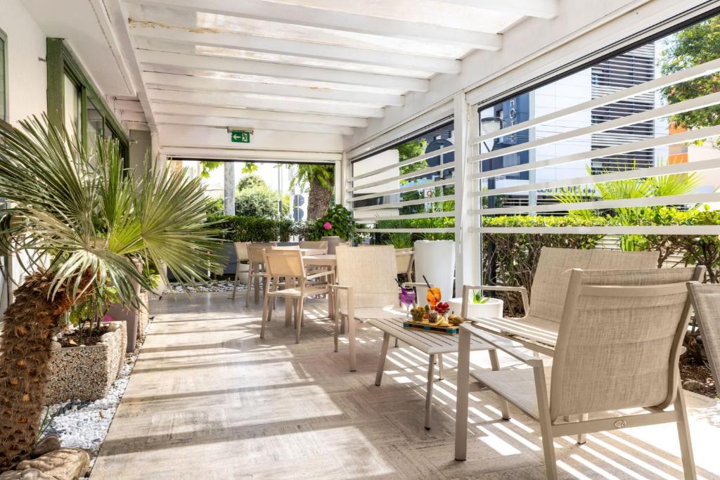 d'une terrasse avec des chaises, des tables et des fenêtres. dans l'établissement Hotel Poker, à Riccione