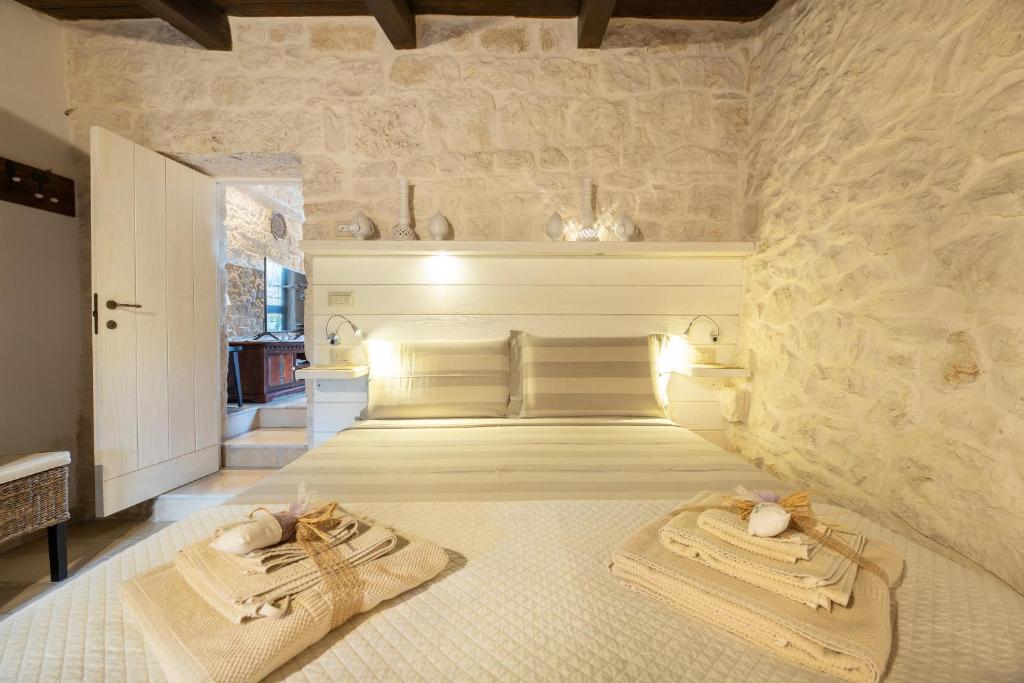 une chambre avec deux lits et un mur en pierre dans l'établissement Trullo Dorato, à Alberobello