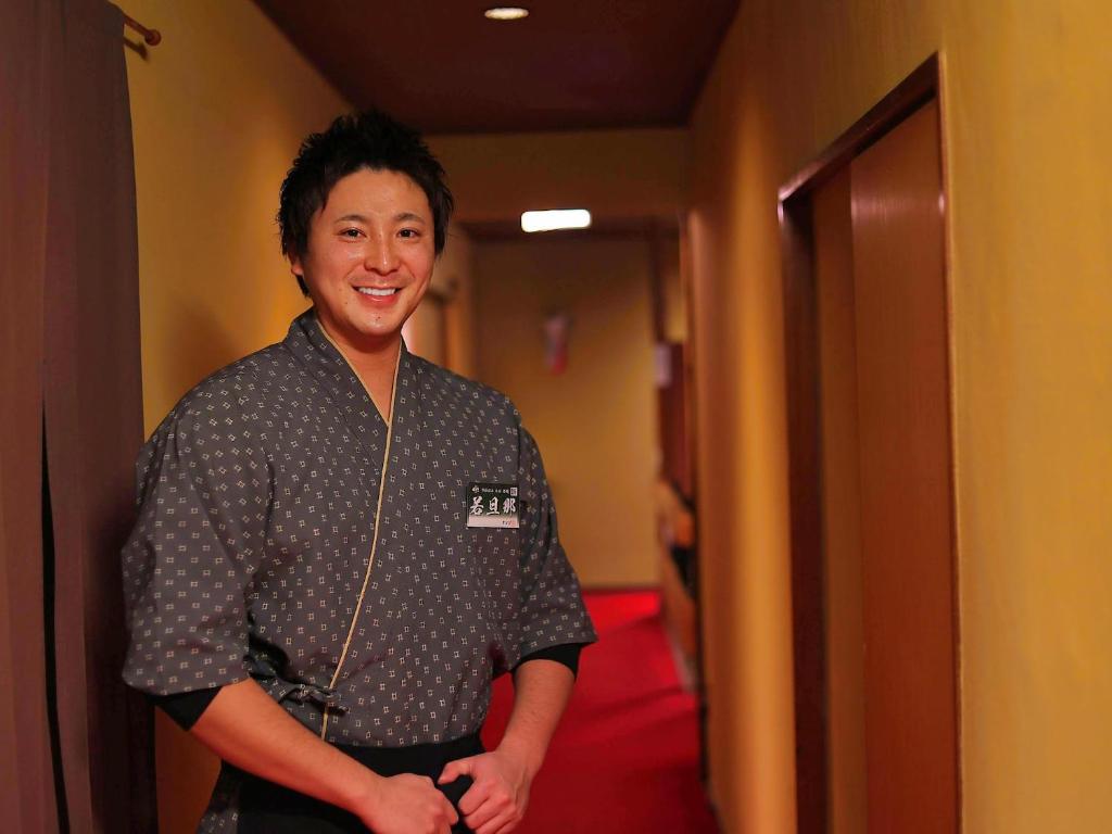 un homme sourit debout dans un couloir dans l'établissement 熱海温泉 法悦 旅館, à Atami 30 autres photos