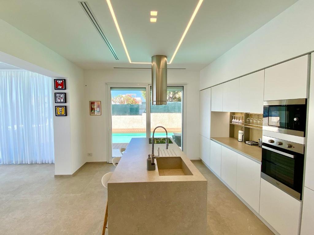 une cuisine avec des armoires blanches et un évier dans l'établissement Villa Lucia - Piscina Privata Riscaldata, à Marina di Ragusa