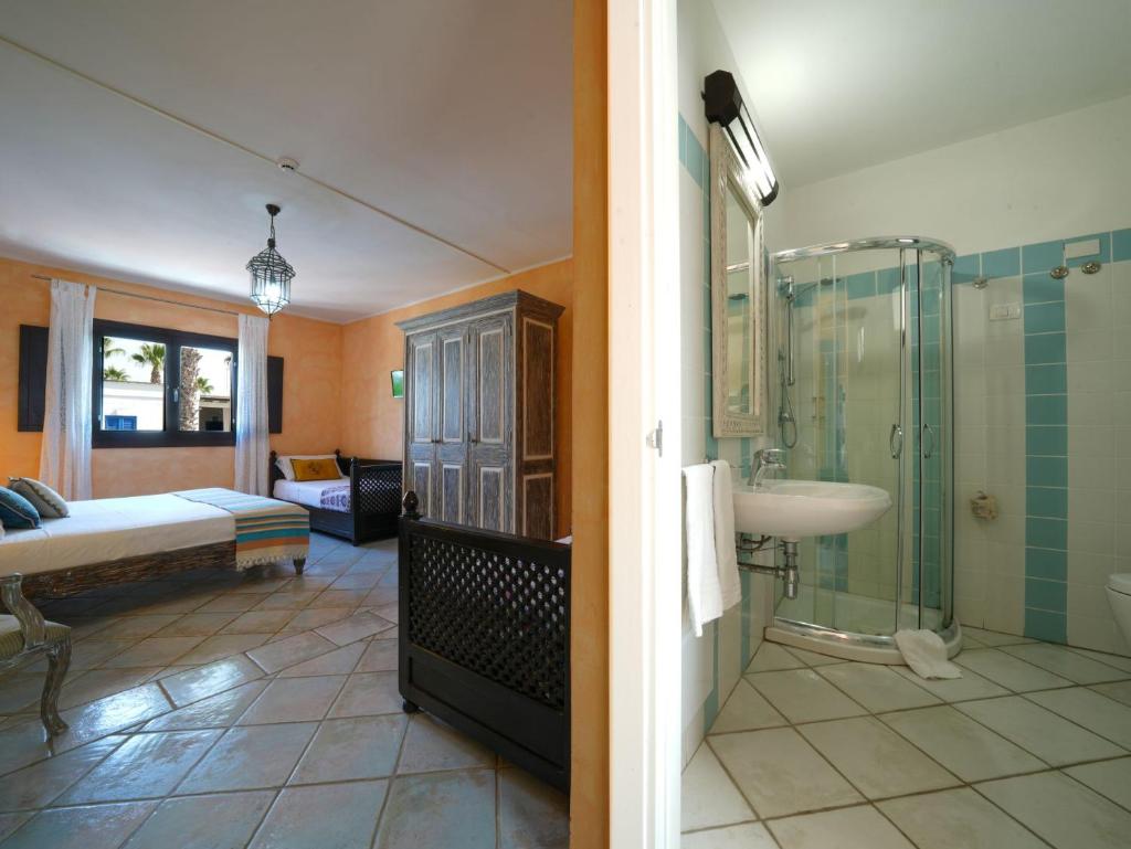 une salle de bain avec douche et lavabo et une chambre dans l'établissement Chiusurelle Village Resort, à Punta Prosciutto
