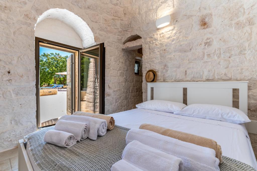 une chambre avec un grand lit blanc et un miroir dans l'établissement Trulli Cocol, à Cocolicchio
