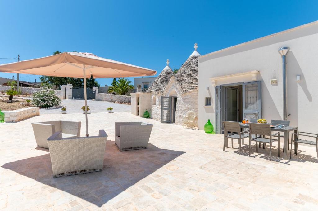 un patio avec un parasol, une table et des chaises dans l'établissement Trulli Cocol, à Cocolicchio