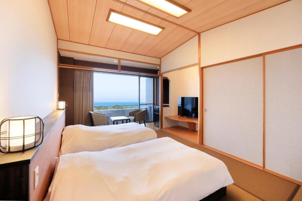 une chambre d'hôtel avec deux lits et une fenêtre dans l'établissement Soratoniwa Atami Izusan, à Atami