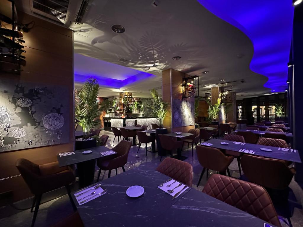 un restaurant avec des tables, des chaises et un éclairage violet dans l'établissement Hotel DOLCEVITA Park & Beach included, à Lido di Jesolo