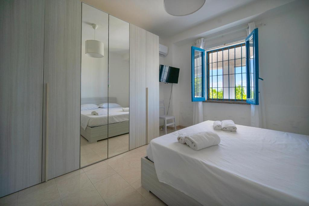 une chambre blanche avec un lit et un miroir dans l'établissement Villa Marzamemi with pool, à Marzamemi