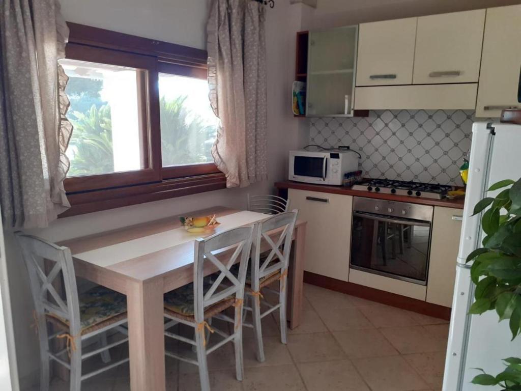 une cuisine avec une table et des chaises et une fenêtre dans l'établissement Villetta BLUE GARDEN, à Sonnino